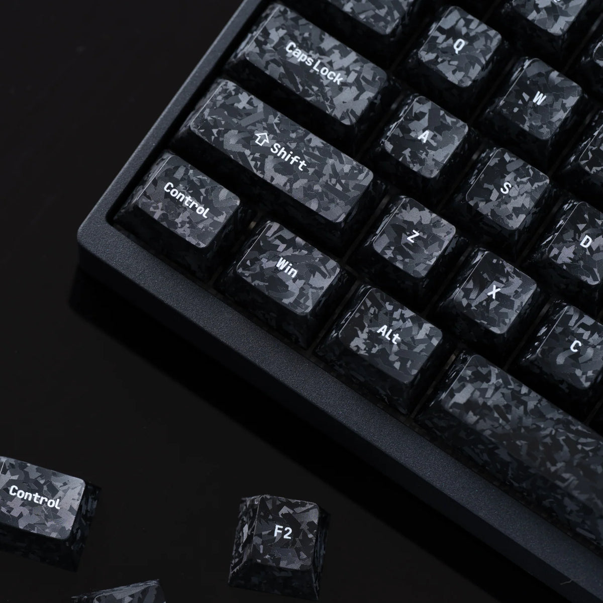 Close-up of the carbon fibre textured modifier keycaps with loose keycaps beside the keyboard