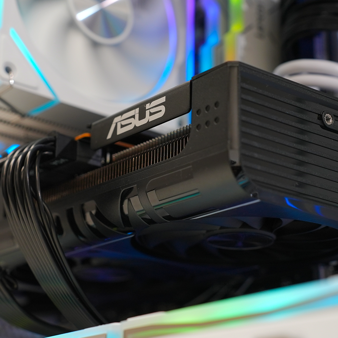 Close-up of an ASUS graphics card inside a sleek gaming PC, showcasing RGB lighting and premium cooling features.